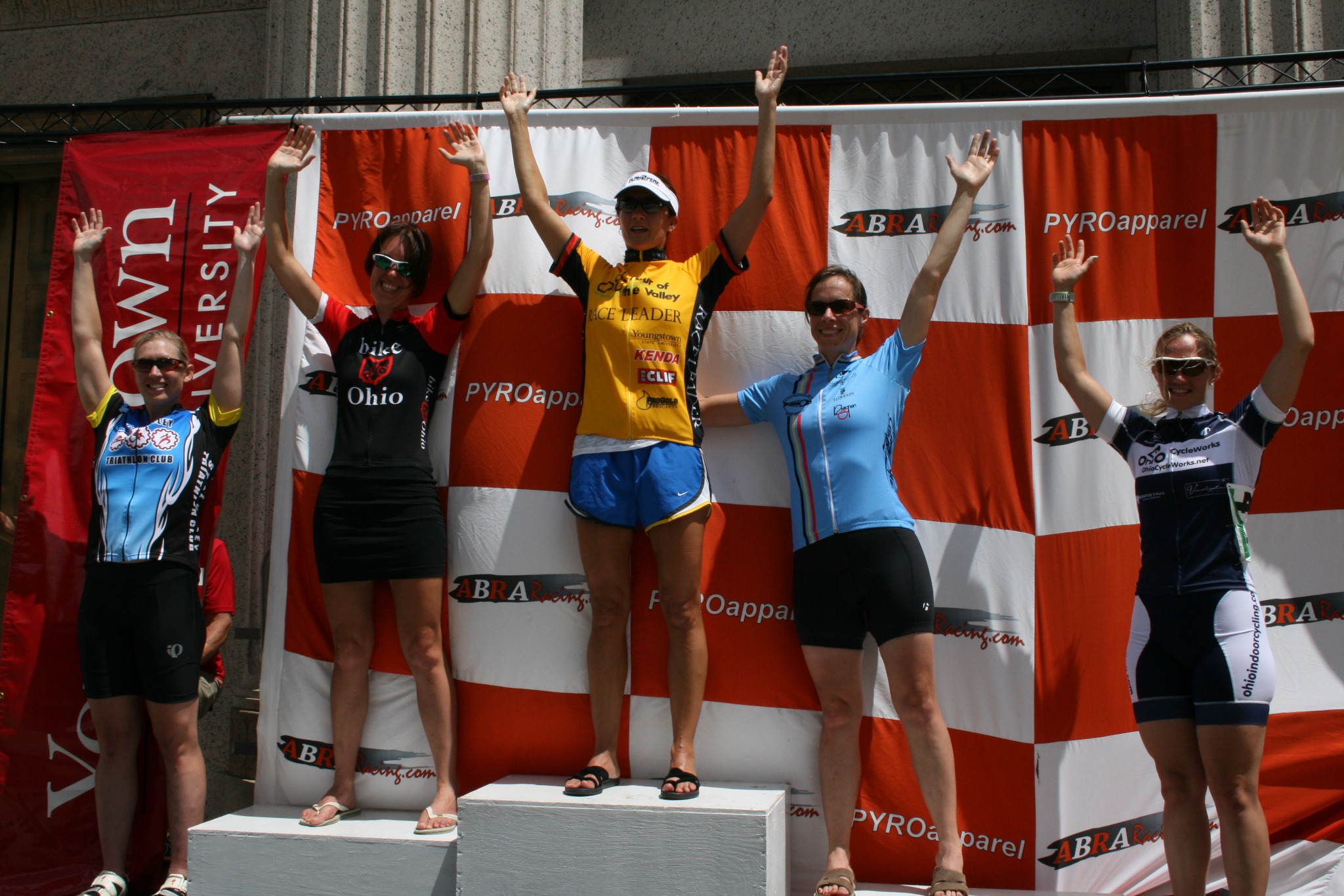 Traci in the yellow race leader jersey at the center of a cycling podium